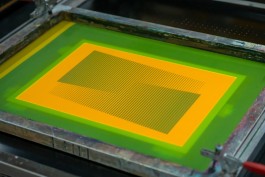 Simplicity Screen. Close-up of a silkscreen frame prepared for printing the navy blue layer of the artwork titled Relationship with audience. The screen features a geometric design of fine vertical lines on a rectangular grid, with a vibrant orange emulsion framed by green tape. The precision suggests a conceptual, graphic approach to layered screen printing.