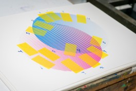 Interdisciplinarity process. Work-in-progress photo of a colourful screenprint from Marçal Prats’ Philosophy series. The print features overlapping magenta and cyan lines creating a purple gradient, forming a circular composition. Yellow test patches and handwritten numbers surround the artwork, indicating colour and alignment checks. The image highlights the layered precision and vibrant experimentation involved in the printmaking process.