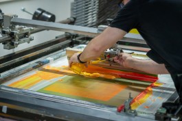 Colour process 02. The author pours vibrant yellow-orange ink onto a mesh frame during the creation of