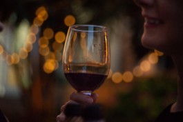Photo of a wine glass closeup with a smile. On the blurred background, there are terrace decorative lights. Photography shooting. Marcal.net Studio