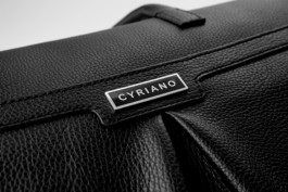Closeup of the metallic logotype badge of a black leather Cyriano Dogwear Outfit Bag. Photography, Branding & Identity.