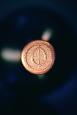 Close up of the OVO bottle. Dark atmosphere, top of the black bottle. View of the tap sealed with gold wax with the OVO logotype engraved.