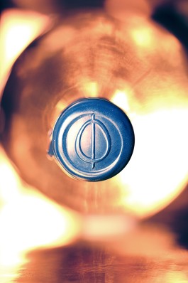 Close up of the OVO bottle. Light atmosphere, top of the transparent bottle. View of the tap sealed with navy blue wax with the OVO logotype engraved.